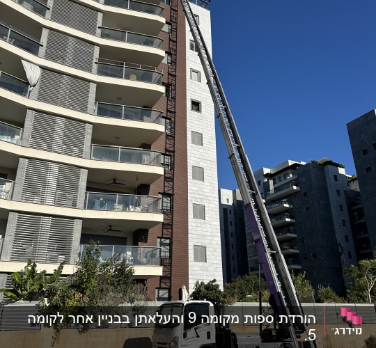 משאית מנוף ליד בניין מגורים גבוה
